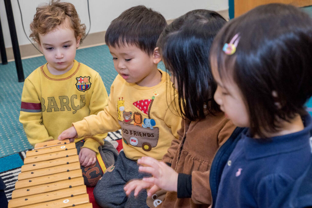 Group of toddlers playing with a xylophone.