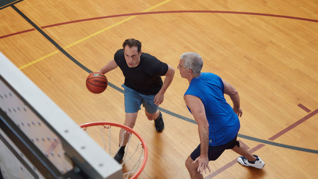 Two adult men playing basketball.