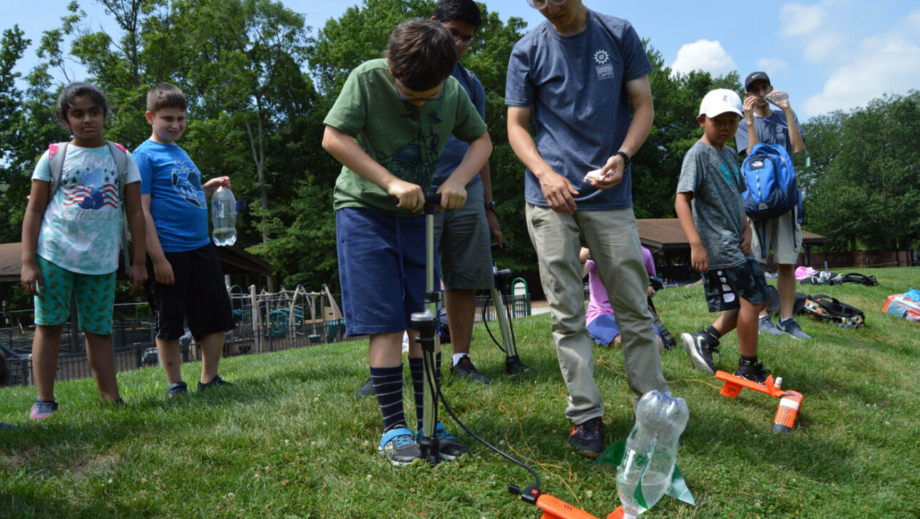Boy using a pump to launch a water rocket.