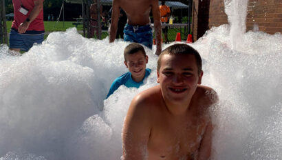 Boys playing in bubbles outside.