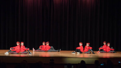 Dance performance on stage in red costumes.