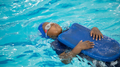 Kid swimming on his back using a kickboard.