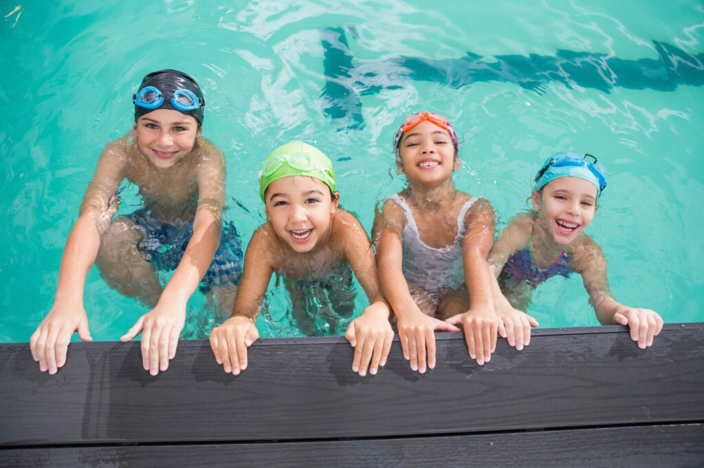 Four kids hanging off the side of the pool.