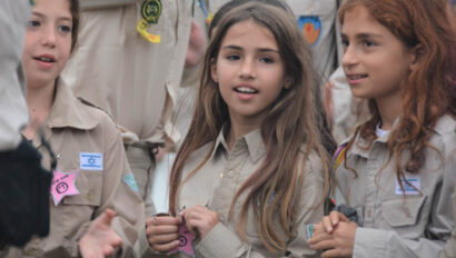 Girls in scout uniforms hanging out together.