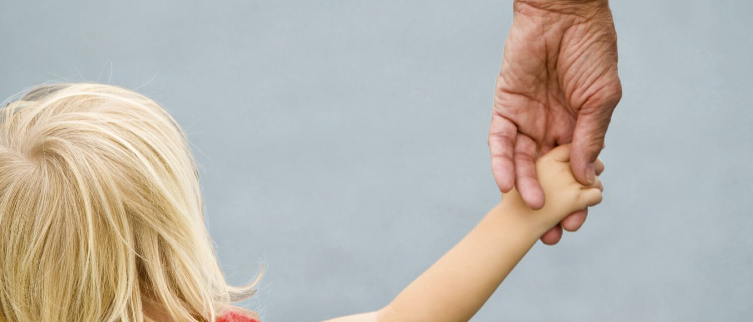 Grandpa holding his toddler granddaughters hand.