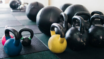 Kettlebells and medicine balls lined up on the floor.