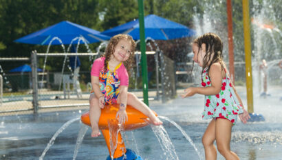 Two kids playing on a water playground.