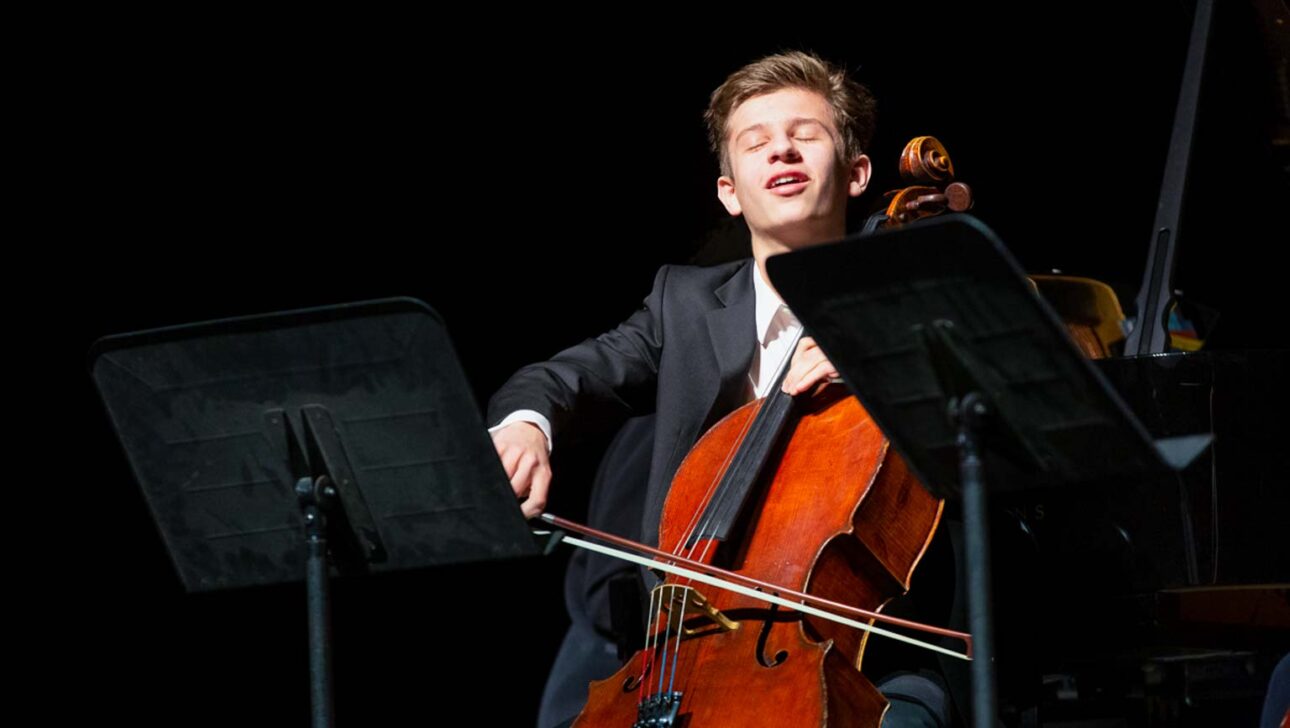 Boy playing a cello onstage.