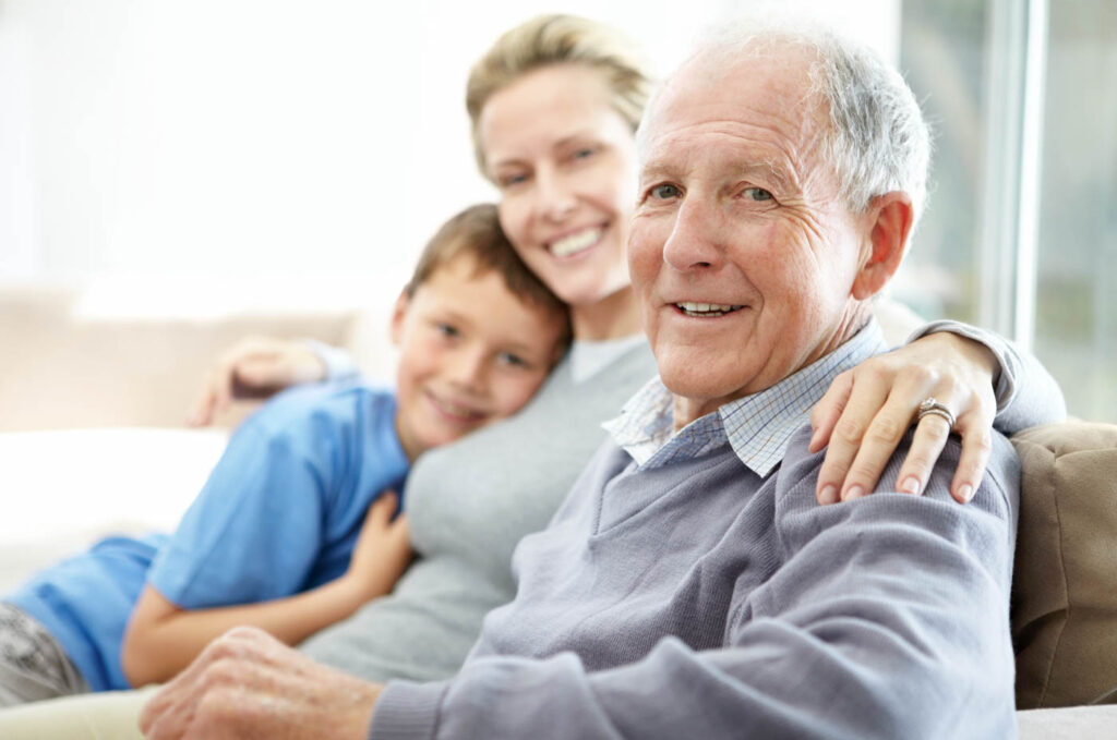 Senior man with his daughter and grandson on a couch.